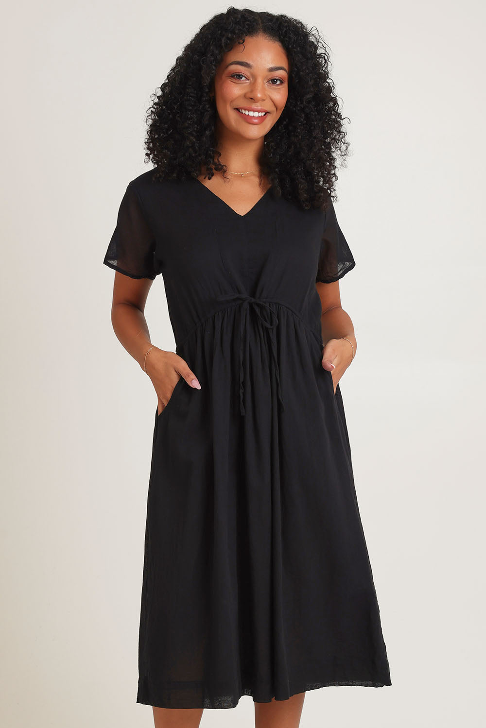 Model Ziara wearing size 10 of the Essentials Tie Waist Cotton Dress in colour Black (Black), from the front, cropped image