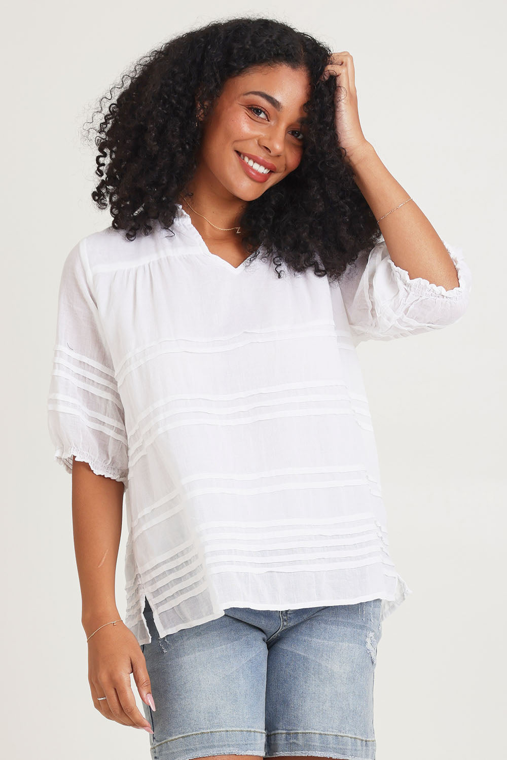 Model Ziara wearing size 10 of the Essentials Organic Cotton Pleated Top in colour White (White), from the front, cropped image
