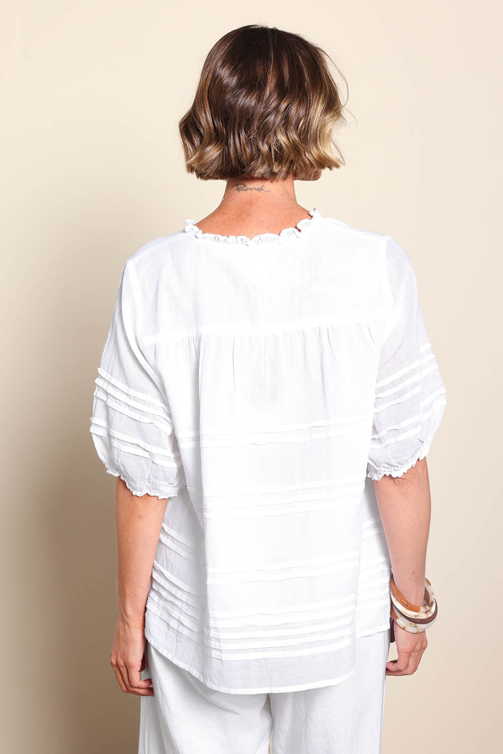 Model Riinar wearing size 10 of the Essentials Pleated Cotton Top - White in colour White, from the back