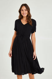 Model Madeline wearing size 10 of the Essentials Godet Short Sleeve Dress in colour Black (Black), from the front, cropped image