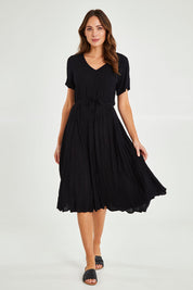Model Madeline wearing size 10 of the Essentials Godet Short Sleeve Dress in colour Black (Black), from the front, showing the whole outfit