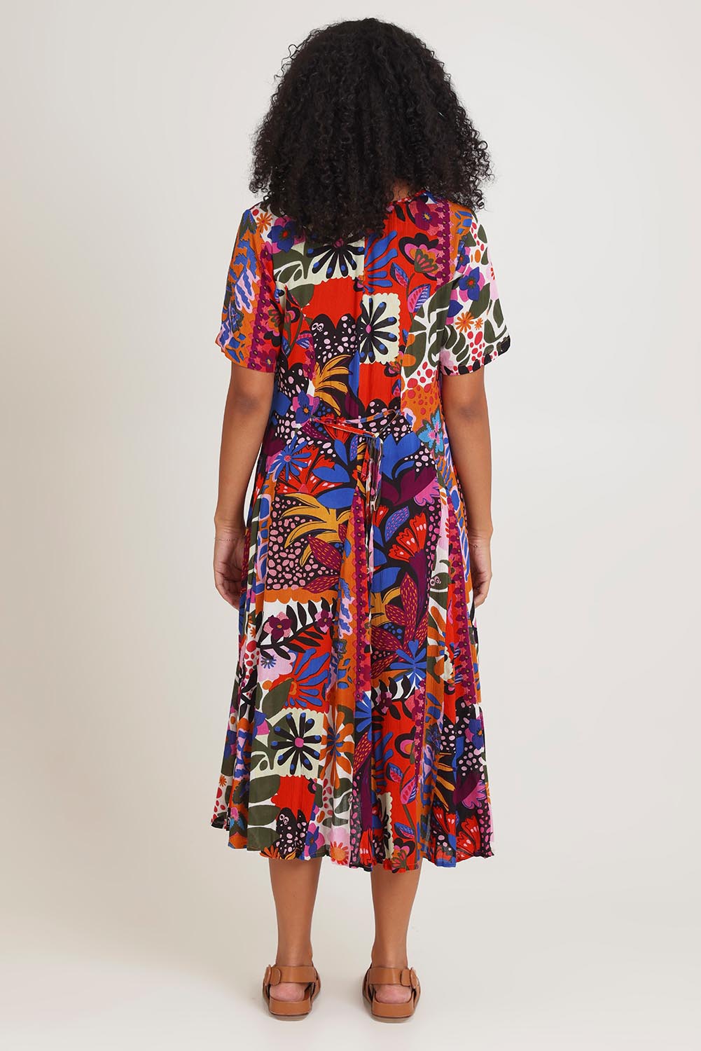 Model Ziara wearing size 10 of the Salvador Short Sleeve Godet Dress in colour Print, from the back