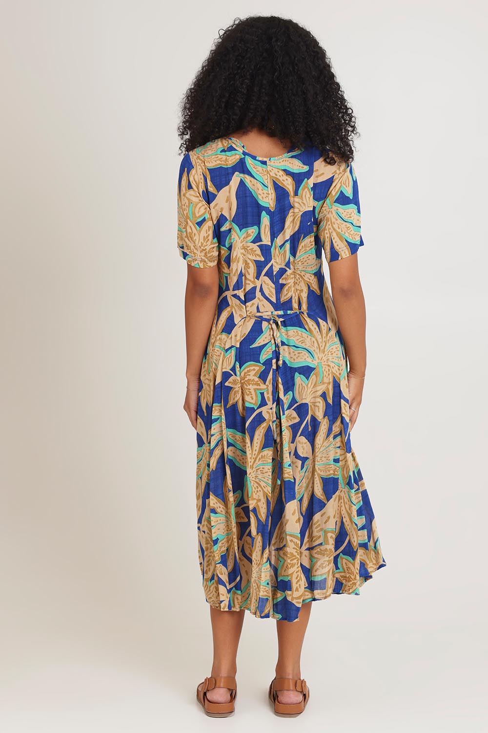 Model Ziara wearing size 10 of the Short Sleeve Godet Dress in colour Blue, from the back
