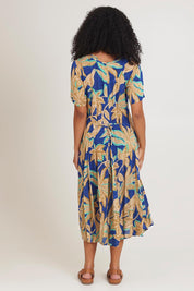 Model Ziara wearing size 10 of the Short Sleeve Godet Dress in colour Blue, from the back