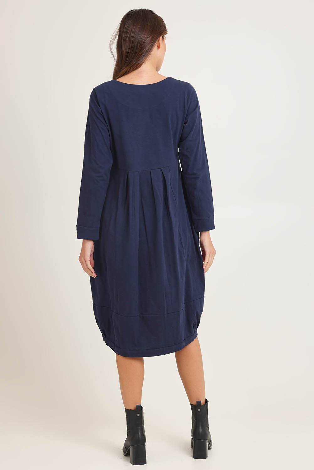 Model Madeline wearing size 10 of the Esssential Knits Yoke Pleated Dress in colour Navy (Blue), from the back