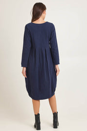 Model Madeline wearing size 10 of the Esssential Knits Yoke Pleated Dress in colour Navy (Blue), from the back