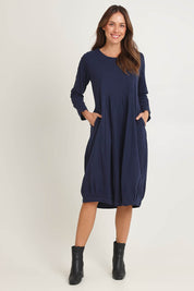 Model Madeline wearing size 10 of the Esssential Knits Yoke Pleated Dress in colour Navy (Blue), from the front, showing the whole outfit