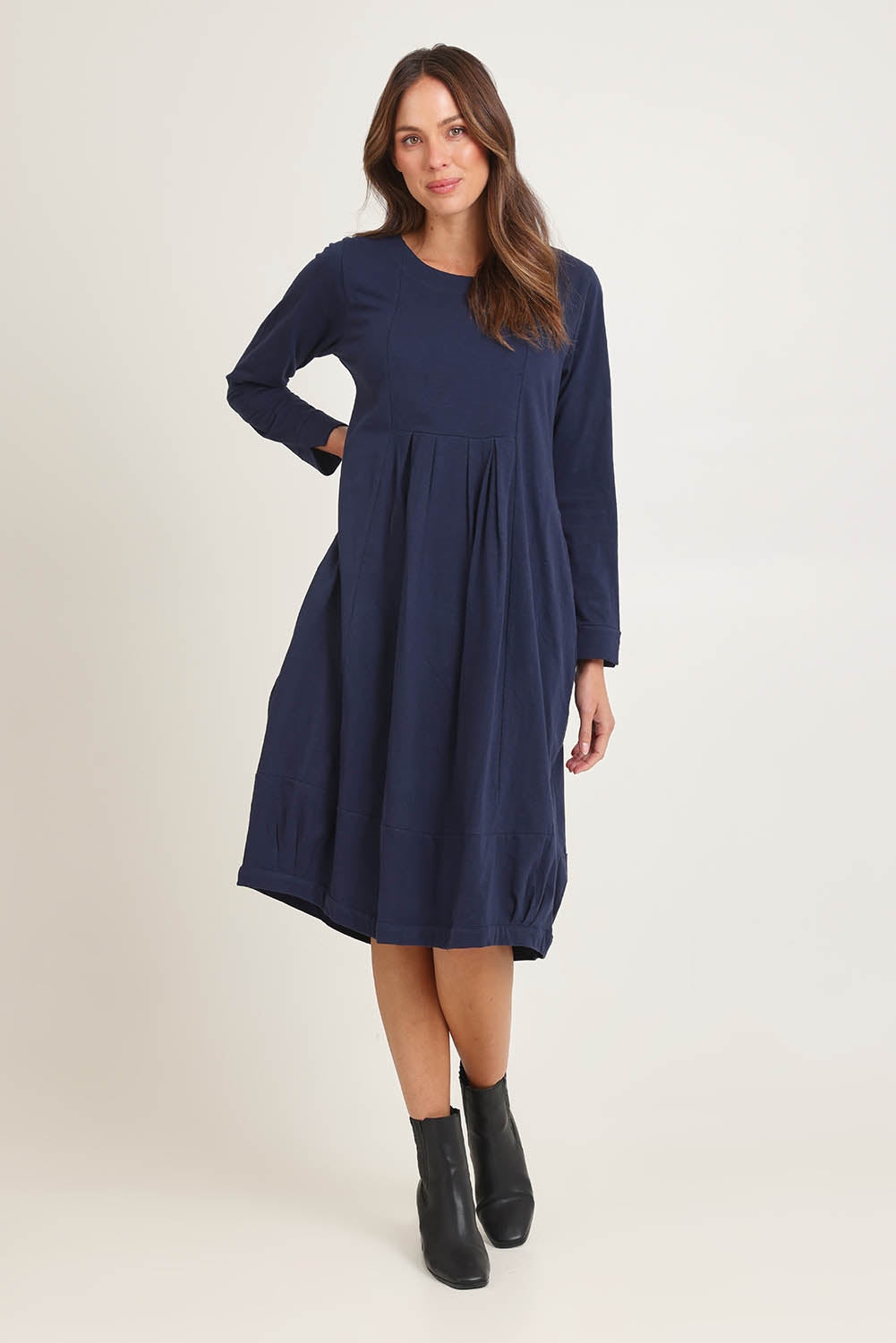 Model Madeline wearing size 10 of the Esssential Knits Yoke Pleated Dress in colour Navy (Blue), from the front, showing the whole outfit