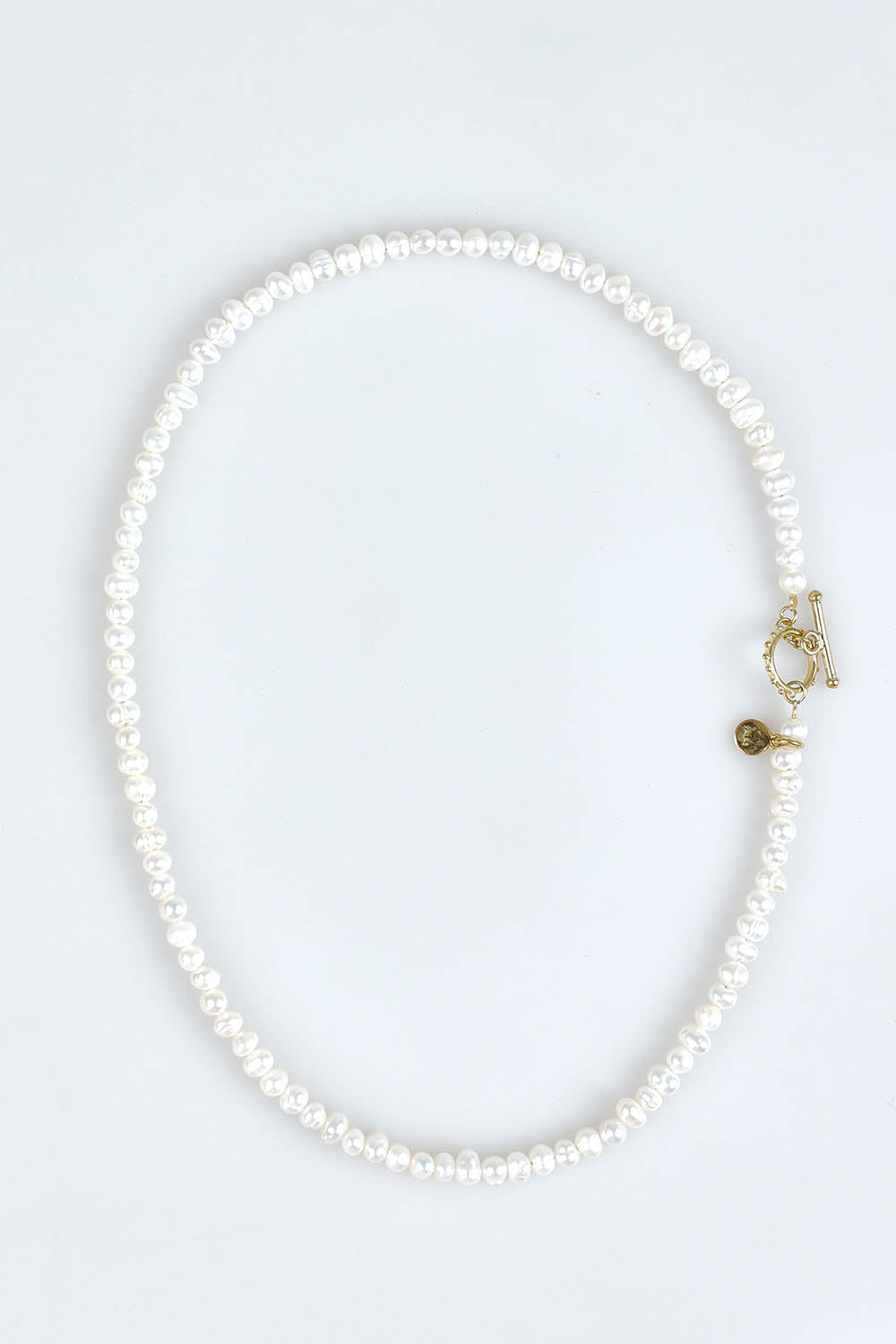 A model wearing the Pearl Fob Necklace in colour Pearl (White), from the front, showing the whole outfit