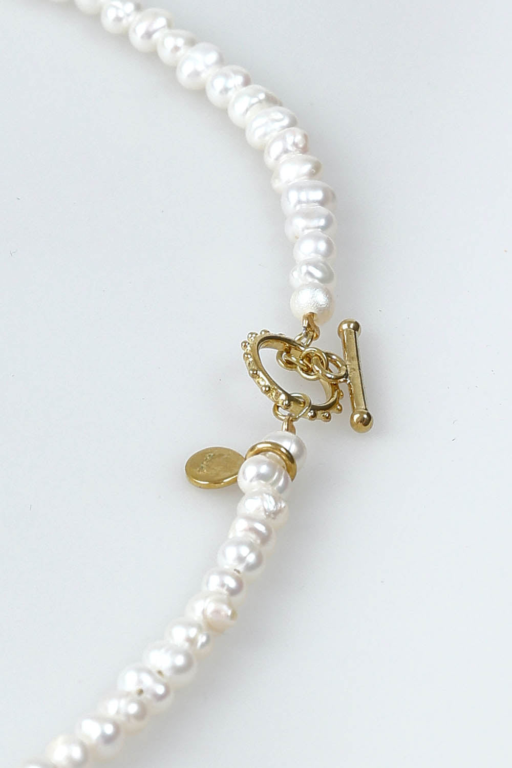 A model wearing the Pearl Fob Necklace in colour Pearl (White), from the front, showing the whole outfit