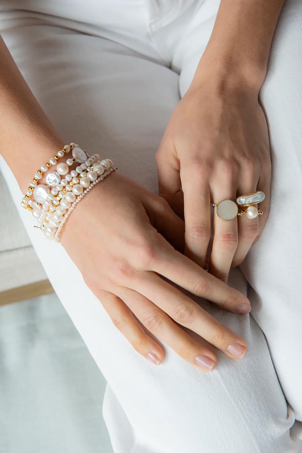 A model wearing the Illuminate Pearl Ring in colour Goldpearl (Metallics), from the front, showing the whole outfit