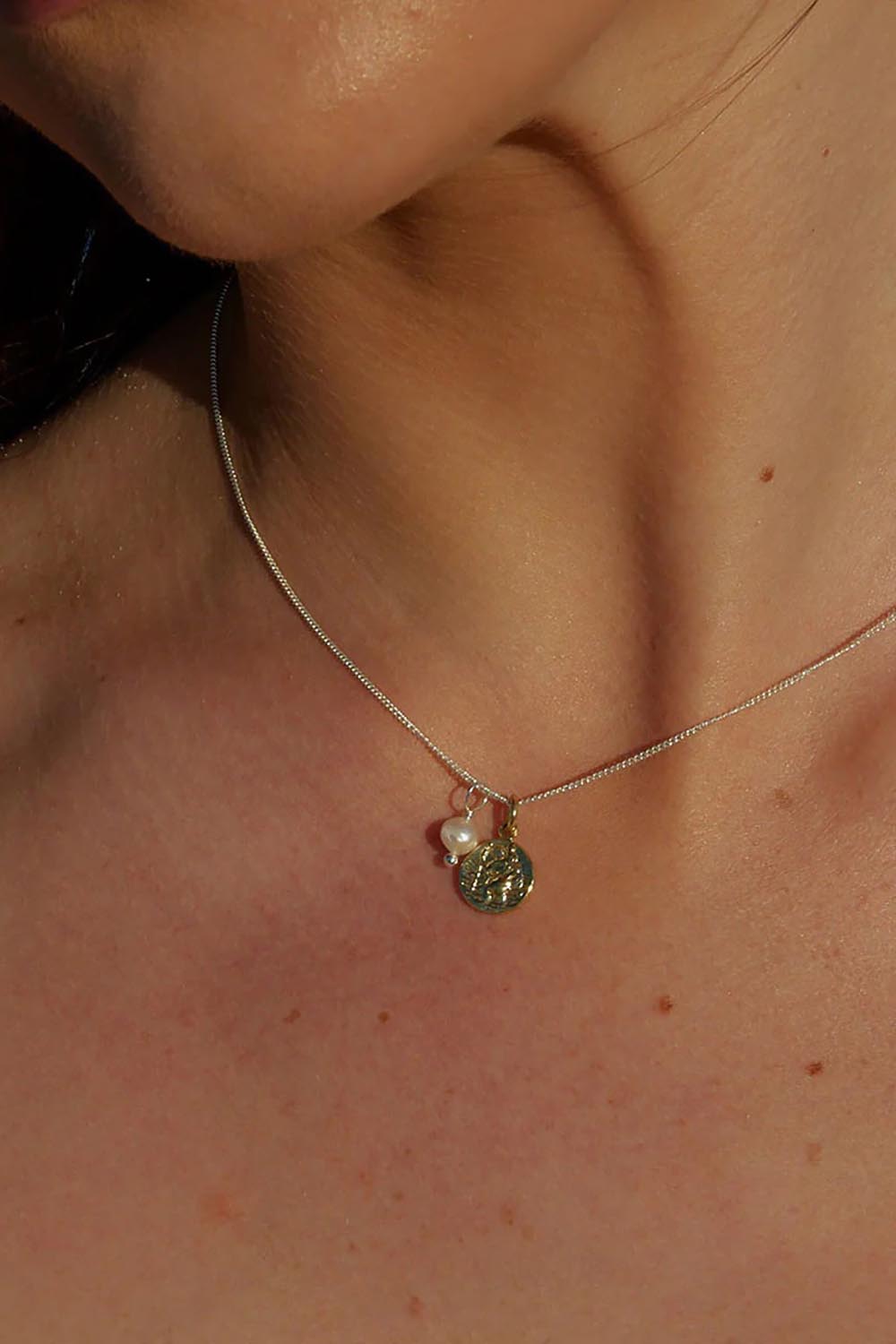 A model wearing the Dreamweaver Necklace in colour Safetravel (Metallics), from the front, showing the whole outfit