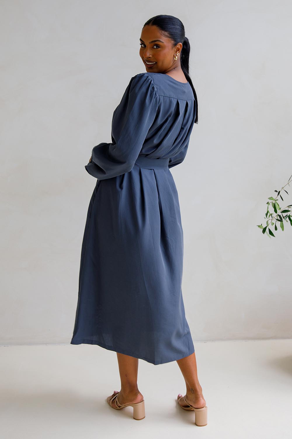 A model wearing the Jade Tencel Dress in colour Storm (Blue), from the back