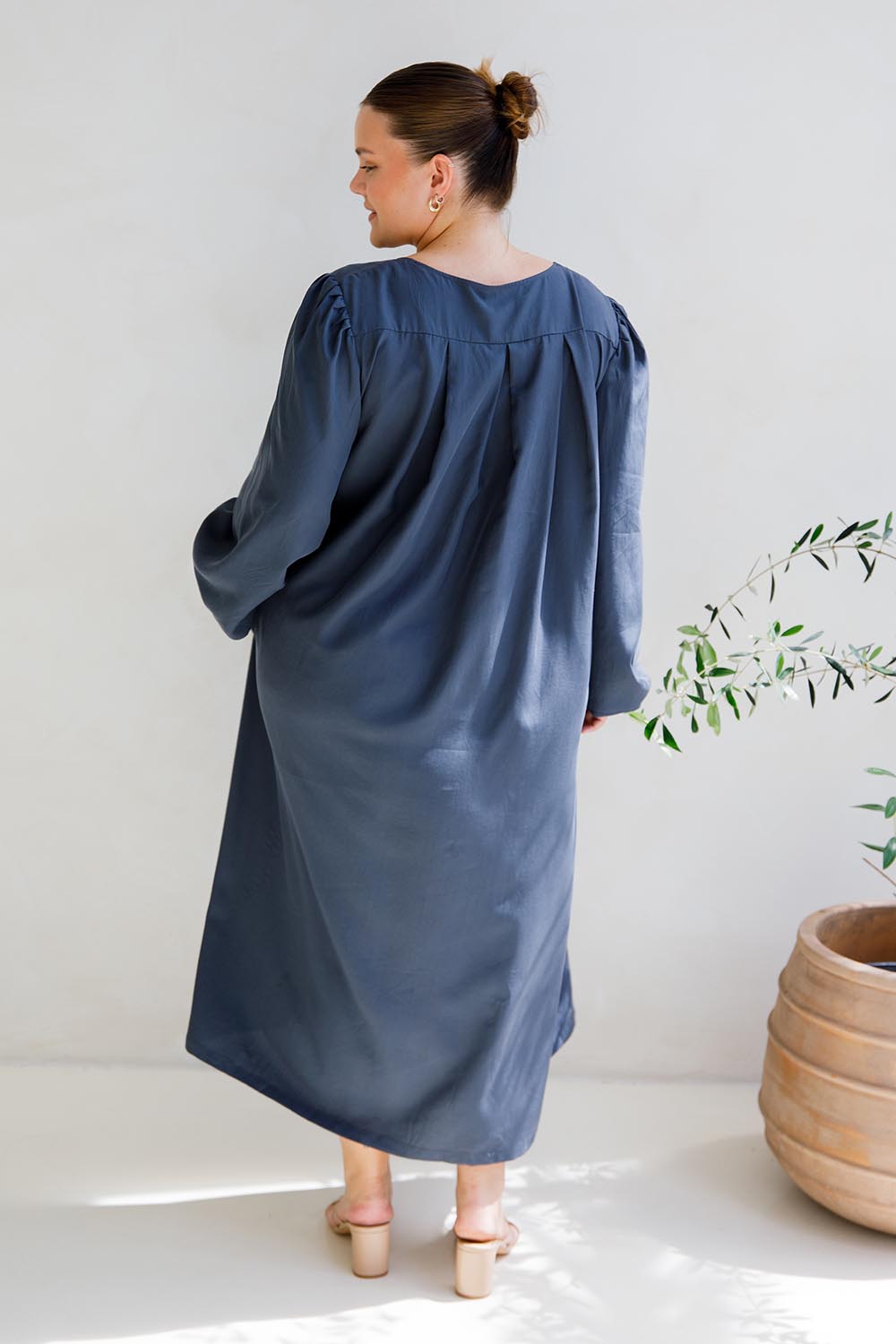 A model wearing the Jade Tencel Dress in colour Storm (Blue), from the back