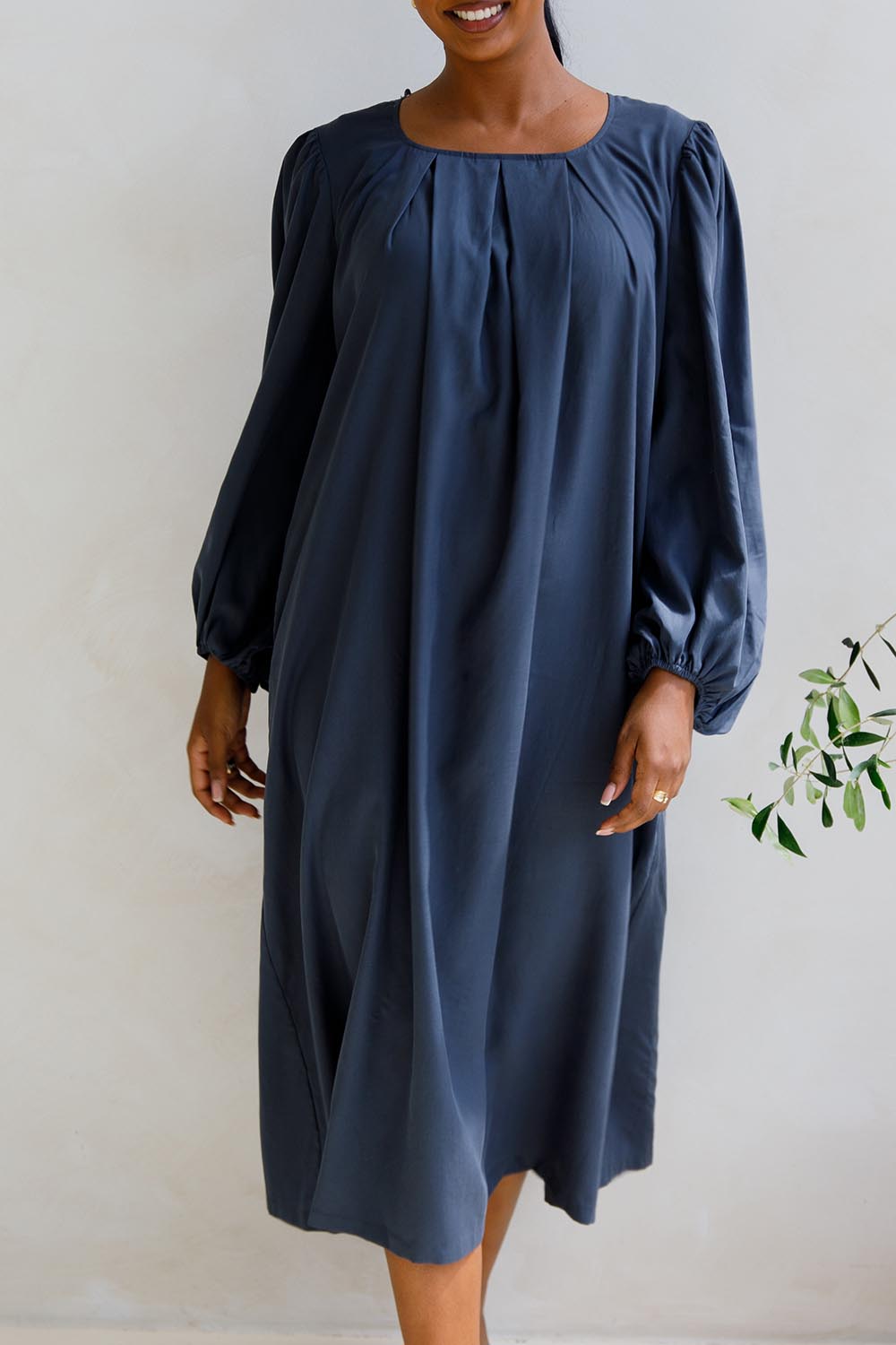 A model wearing the Jade Tencel Dress in colour Storm (Blue), from the front, cropped image