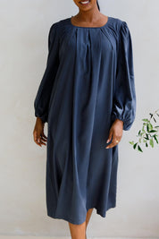 A model wearing the Jade Tencel Dress in colour Storm (Blue), from the front, cropped image