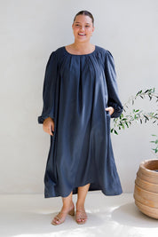 A model wearing the Jade Tencel Dress in colour Storm (Blue), from the front, showing the whole outfit