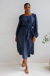 A model wearing the Jade Tencel Dress in colour Storm (Blue), from the front, showing the whole outfit