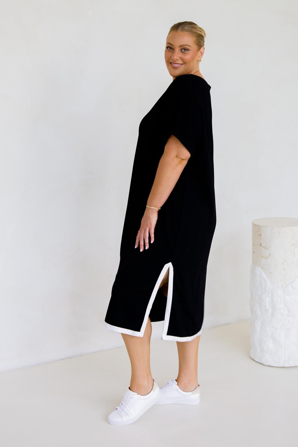 A model wearing the Gigi Lounge Dress in colour Black (Black), from the back