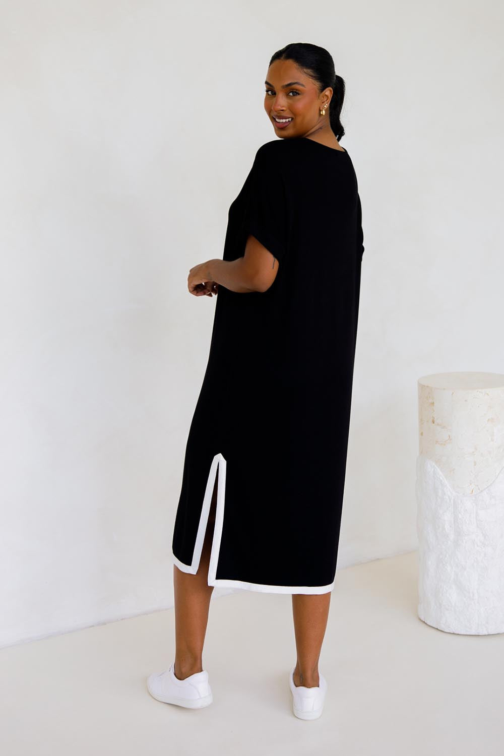 A model wearing the Gigi Lounge Dress in colour Black (Black), from the back