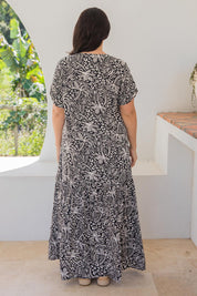 A model wearing the Peak Maxi Dress in colour Blkpalm (Black), from the back