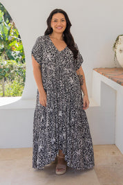 A model wearing the Peak Maxi Dress in colour Blkpalm (Black), from the front, showing the whole outfit