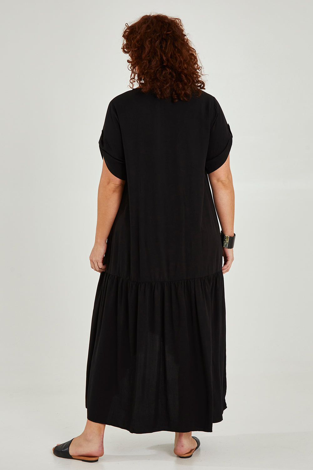 Model Maddy wearing the Short Sleeve Peak Maxi Dress in colour Black (Black), from the back