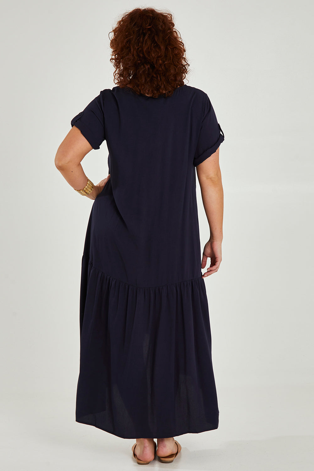 Model Maddy wearing the Short Sleeve Peak Maxi Dress in colour Navy (Blue), from the back