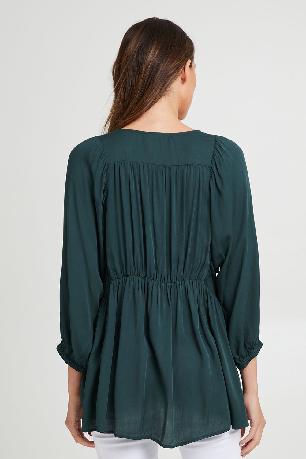 Model Madeline wearing size S of the Charlie Top in colour Peacock (Green), from the back
