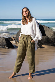 A model wearing the Olivia Pant in colour Greenenvy (Green), from the front, showing the whole outfit