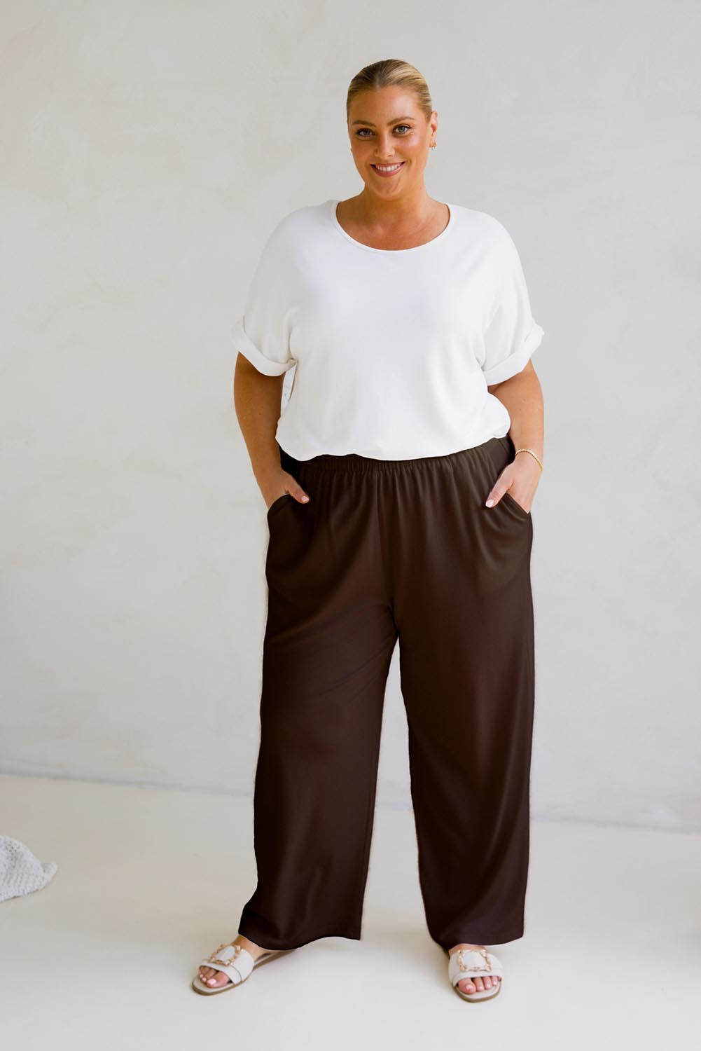 A model wearing the Gigi Lounge Pant in colour Chocolate, from the front, showing the whole outfit
