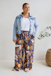 A model wearing the Aspen Pants in colour Darkpalme, from the front, showing the whole outfit