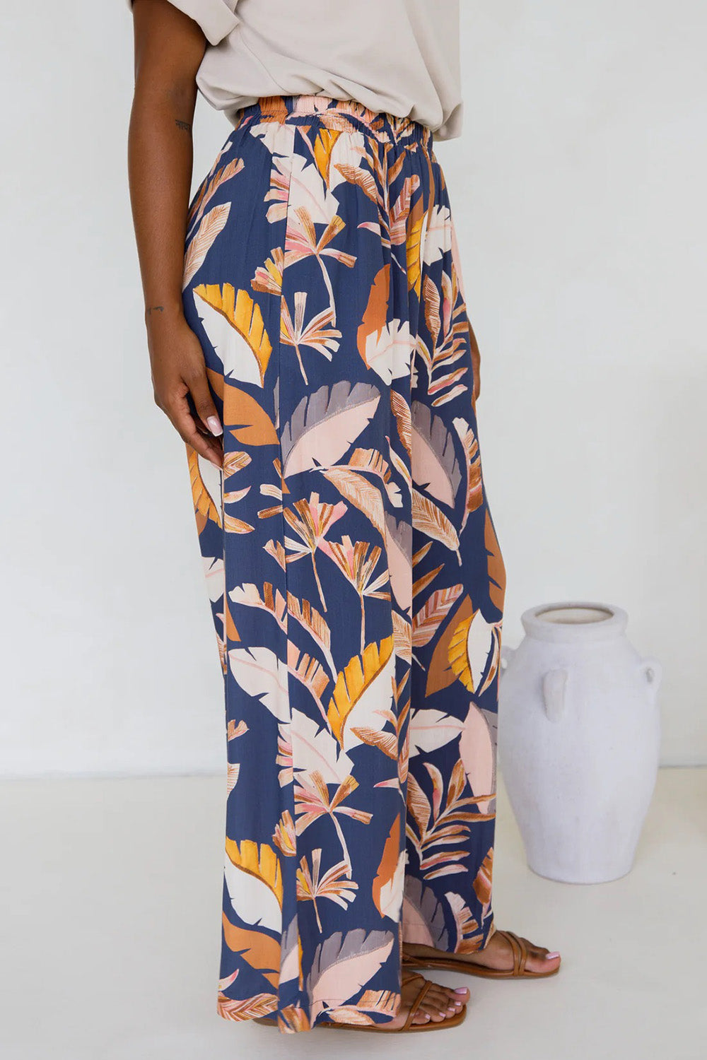 A model wearing the Aspen Pants in colour Darkpalme, from the front, showing the whole outfit