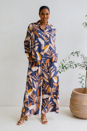 A model wearing the Aspen Pants in colour Darkpalme, from the front, showing the whole outfit
