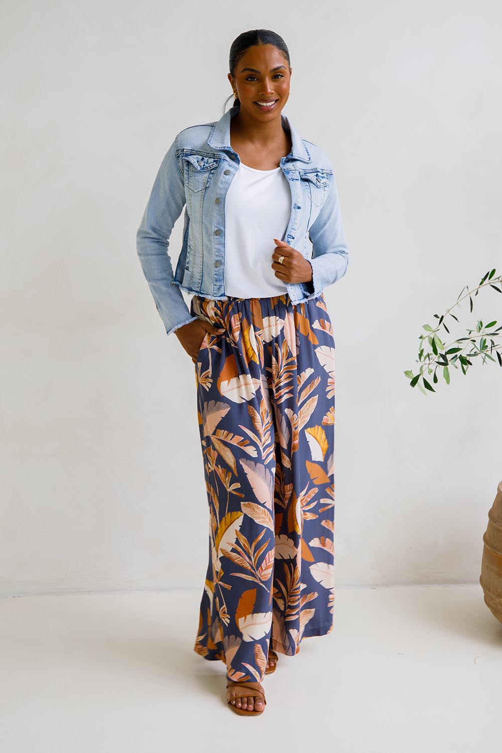 A model wearing the Aspen Pants in colour Darkpalme, from the front, showing the whole outfit