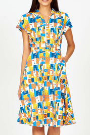 A model wearing the Kelly Dress in colour Houses (Blue), from the front, cropped image