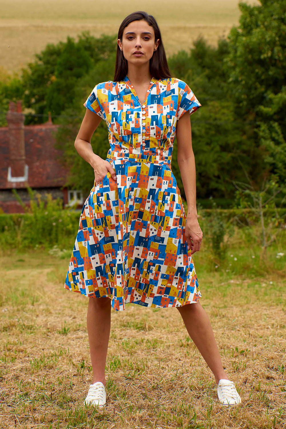A model wearing the Kelly Dress in colour Houses (Blue), from the front, showing the whole outfit