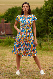A model wearing the Kelly Dress in colour Houses (Blue), from the front, showing the whole outfit