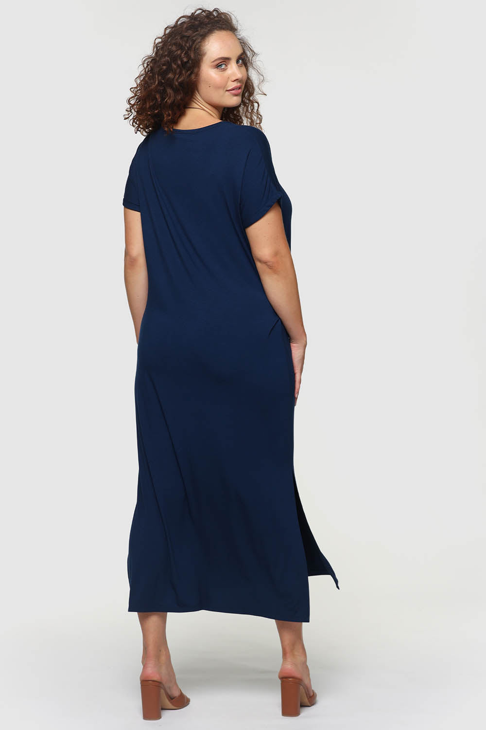 A model wearing the Elsie Dress in colour Navy (Blue), from the back