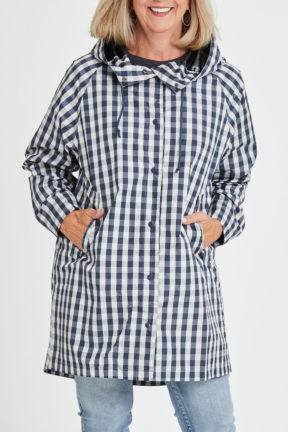 Model Sandy wearing size S of the Rosie Raincoat in colour Navychequ (Blue), from the front, cropped image