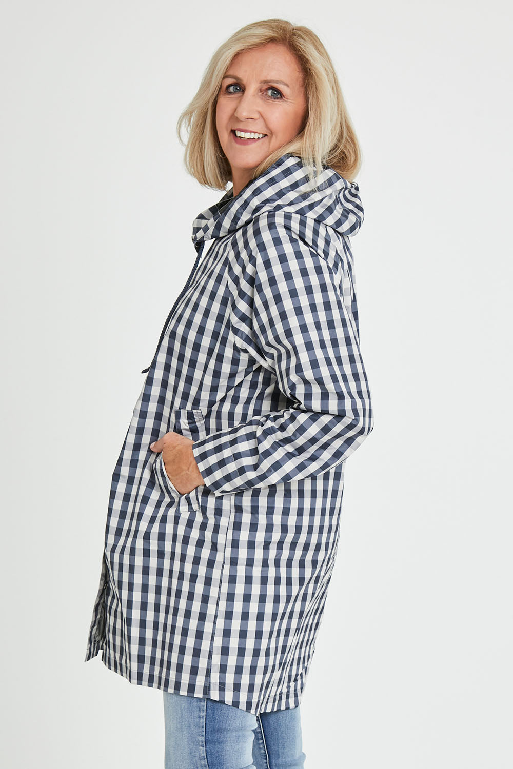 Model Sandy wearing size S of the Rosie Raincoat in colour Navychequ (Blue), from the front, cropped image