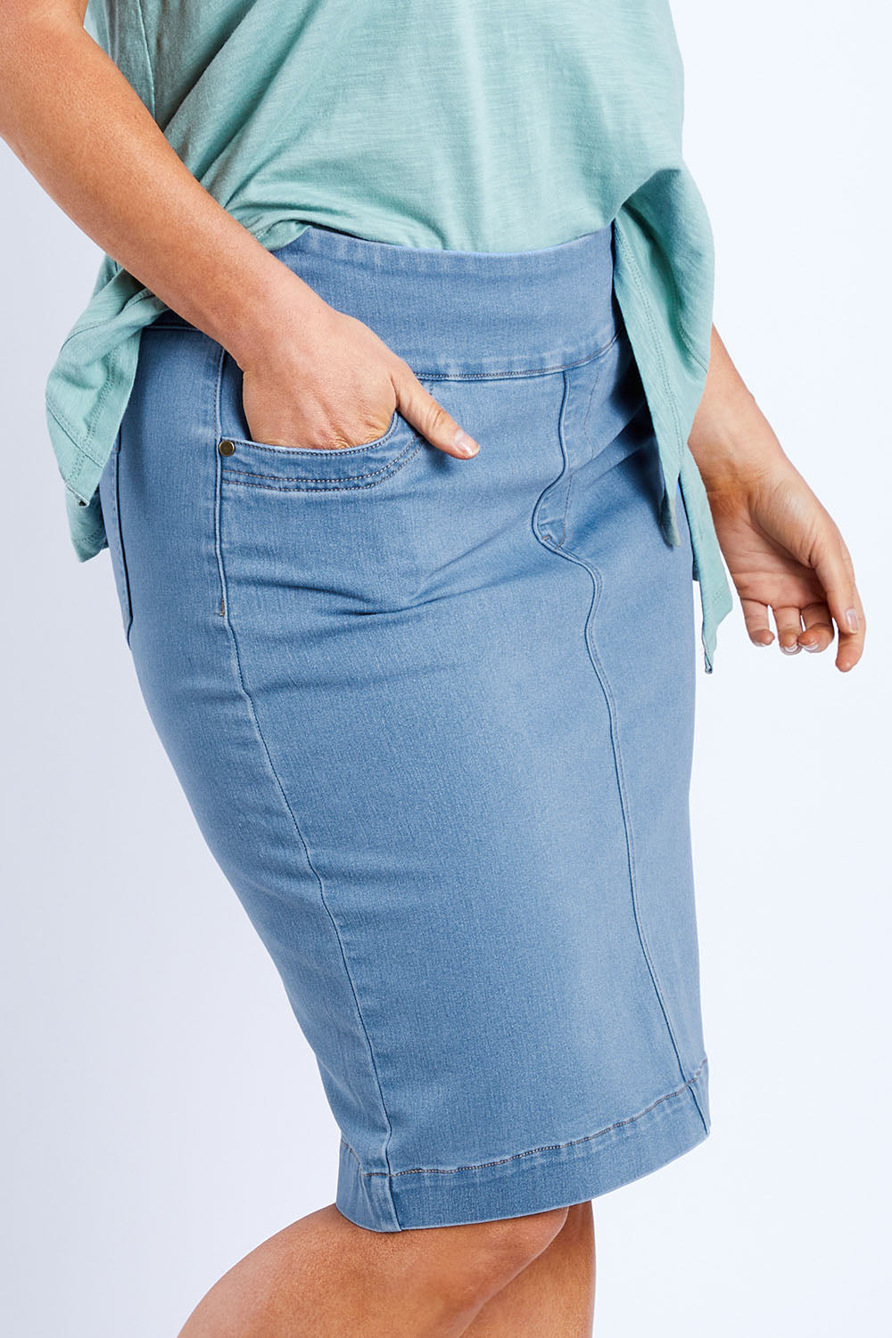 Model Laura wearing size 14 of The Pull On Denim Skirt in colour Lightdenim (Blue), from the front, cropped image