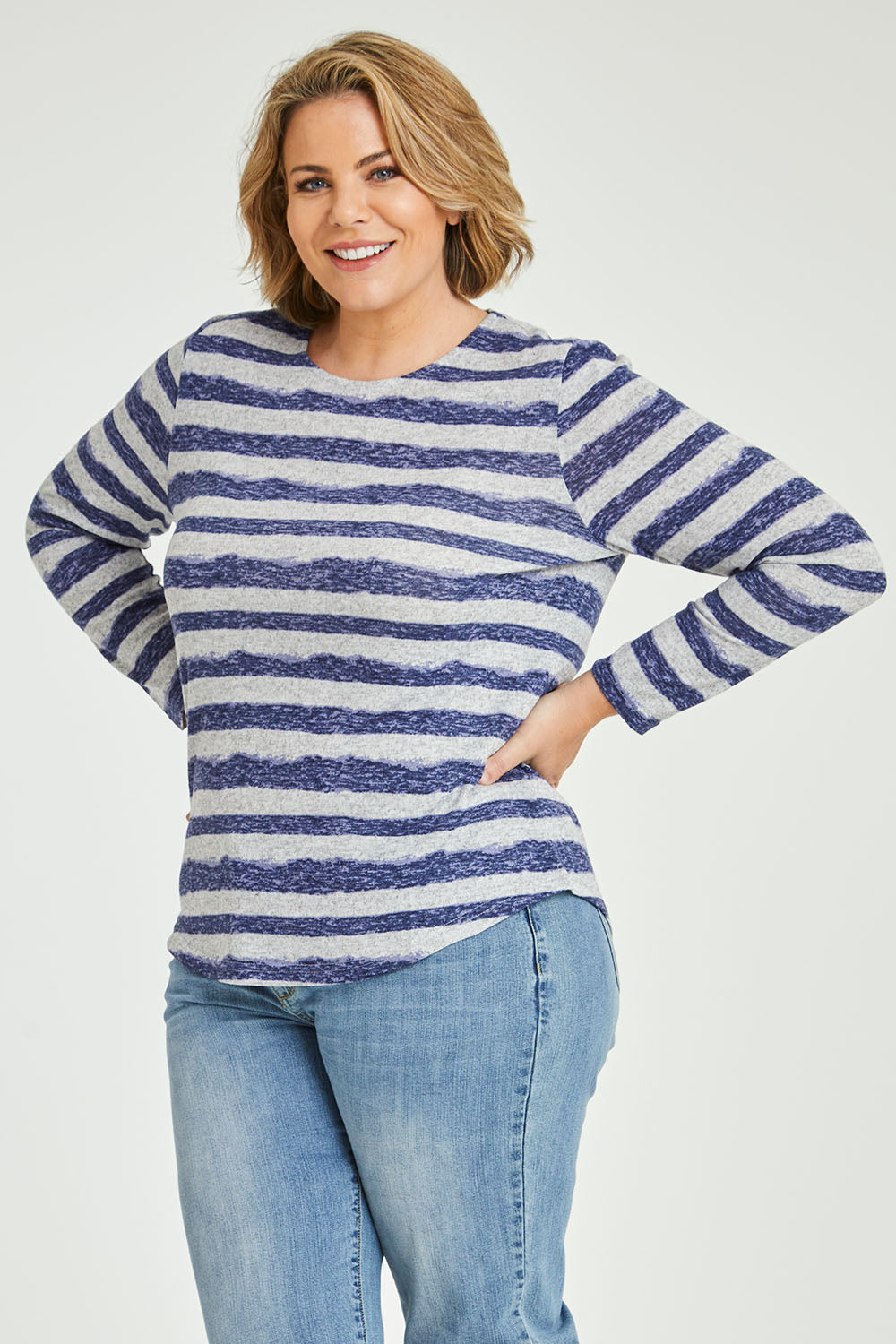 Model Fiona wearing size 16 of The Striped Curved Hem Long Sleeve Tee in colour Cornflower (Blue), from the front, cropped image