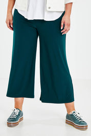 Model Jess wearing size 14 of The Recycled Relax Fit Pant in colour Deeplagoon (Green), from the front, cropped image
