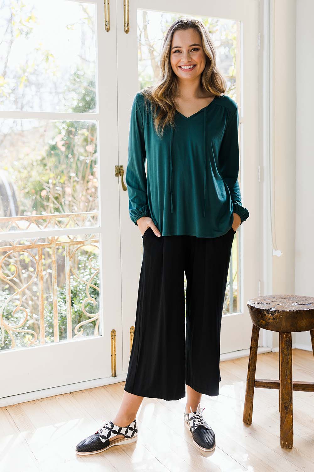 Model Tahlia wearing size 10 of The V Neck Tie Top in colour Juniper (Green), from the front, showing the whole outfit
