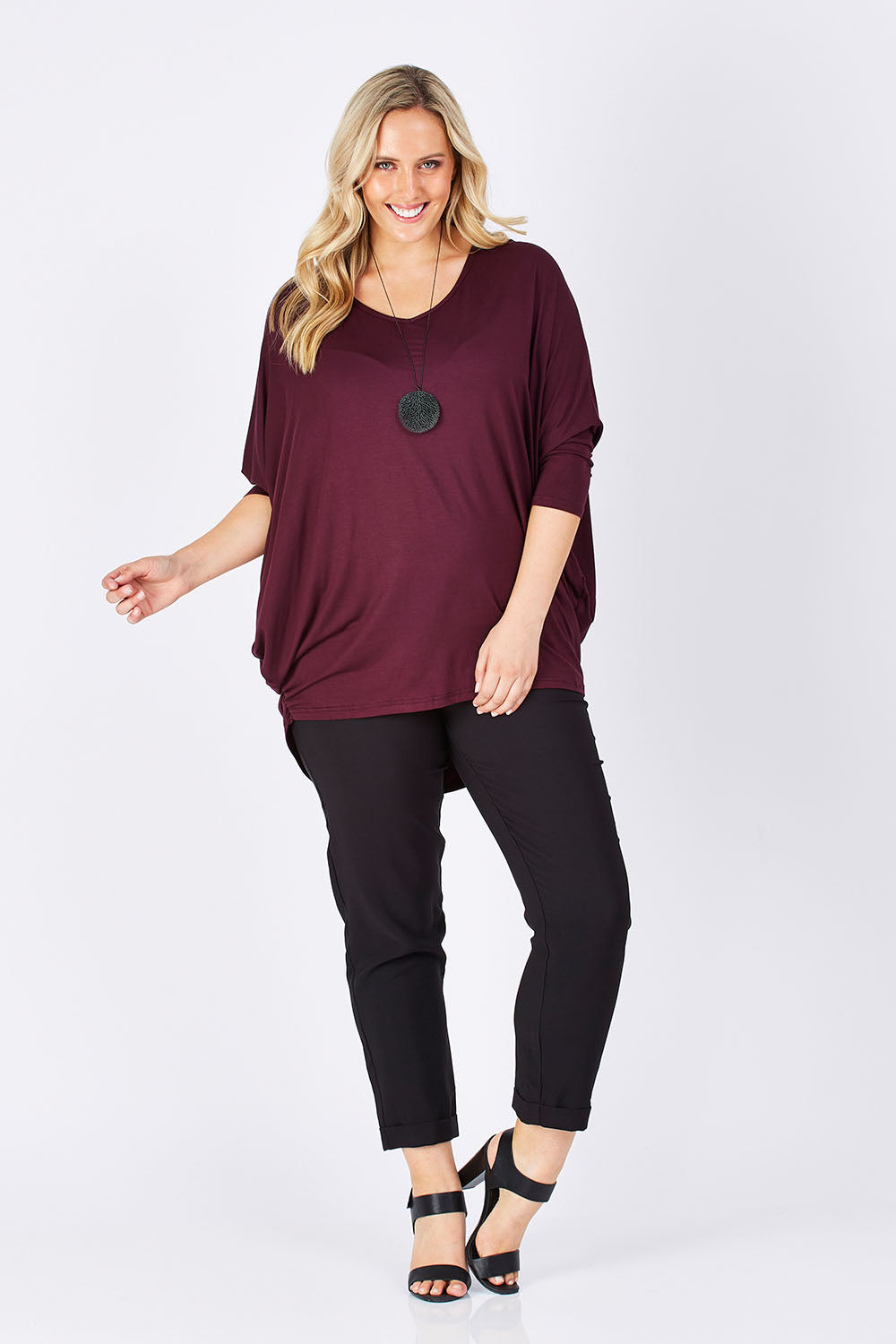 Model Jess wearing size 14 of The V Neck Side Drape Tee in colour Wine (Purple), from the front, showing the whole outfit
