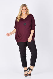 Model Jess wearing size 14 of The V Neck Side Drape Tee in colour Wine (Purple), from the front, showing the whole outfit