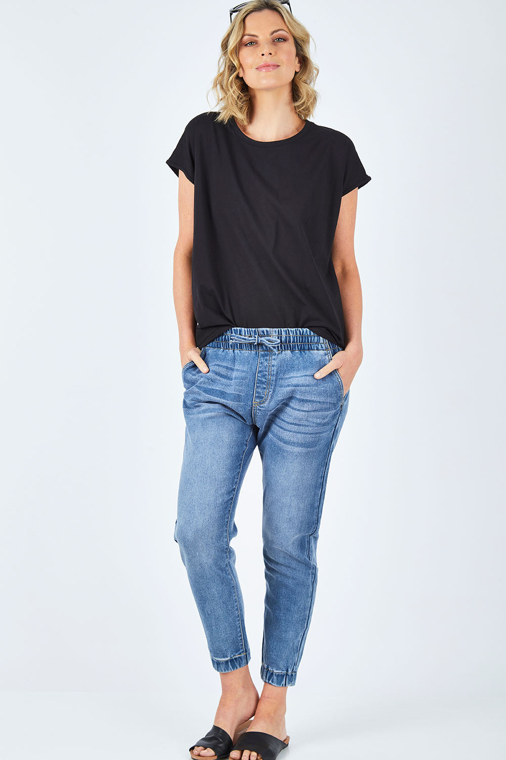 Model Chelsea wearing size 10 of The Pull On Jogger Jean in colour Denim (Blue), from the front, showing the whole outfit