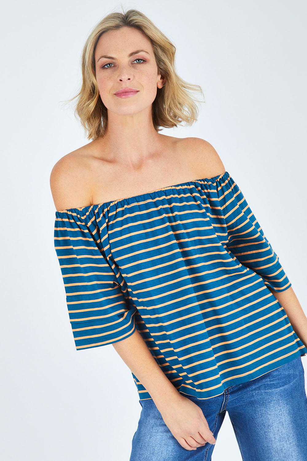 Model Chelsea wearing size 10 of The Cotton Bamboo Free Shoulder Top in colour Bluegold (Blue), from the front, cropped image
