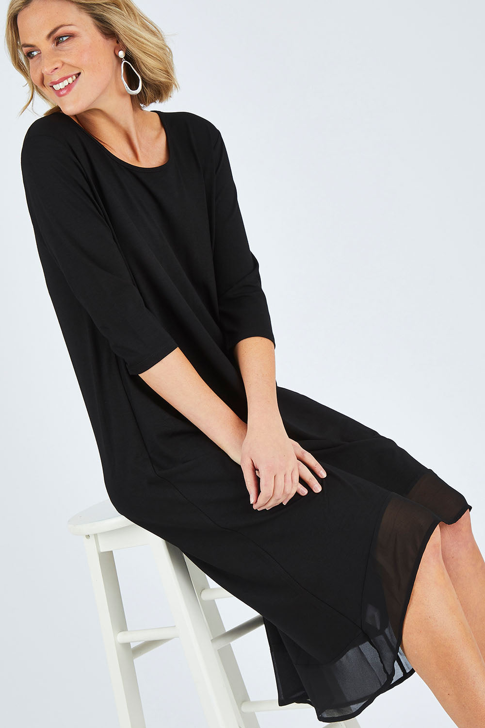 Model Chelsea wearing size 10 of The Chiffon Trim Dress in colour Black (Black), from the front, cropped image